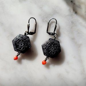 Intricate detailed black earrings with orange bead drop